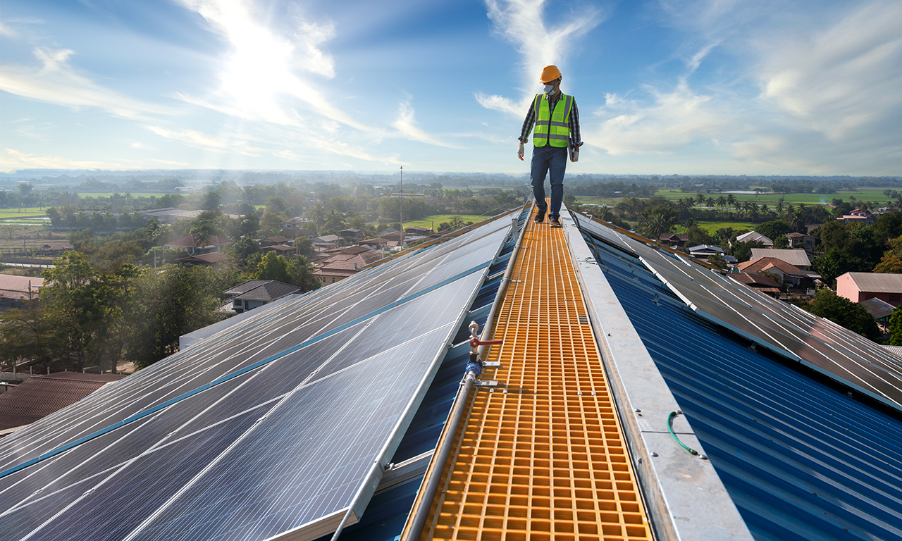 A worker inspecting solar panels on a roof