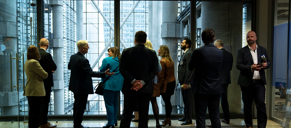 Some of the group are looking out of a large glass window into the Lloyd's Atrium