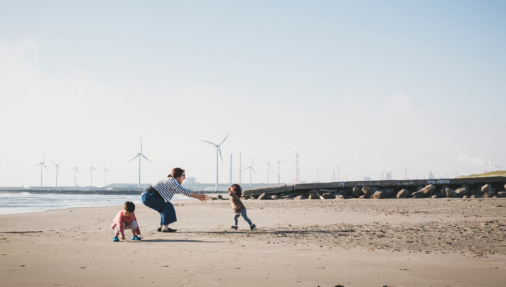 A family on the beach with wind turbines in the background